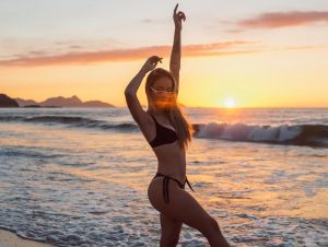 woman in swimsuit dancing on beach