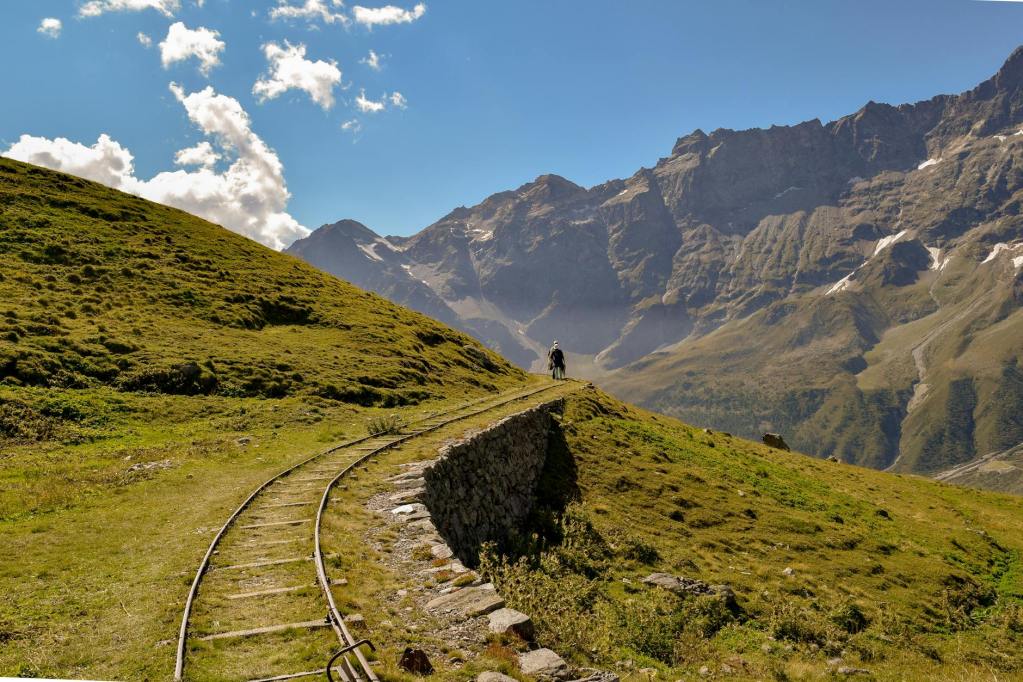 ferrovia grigia vicino a una verde collina erbosa durante una giornata nuvolosa