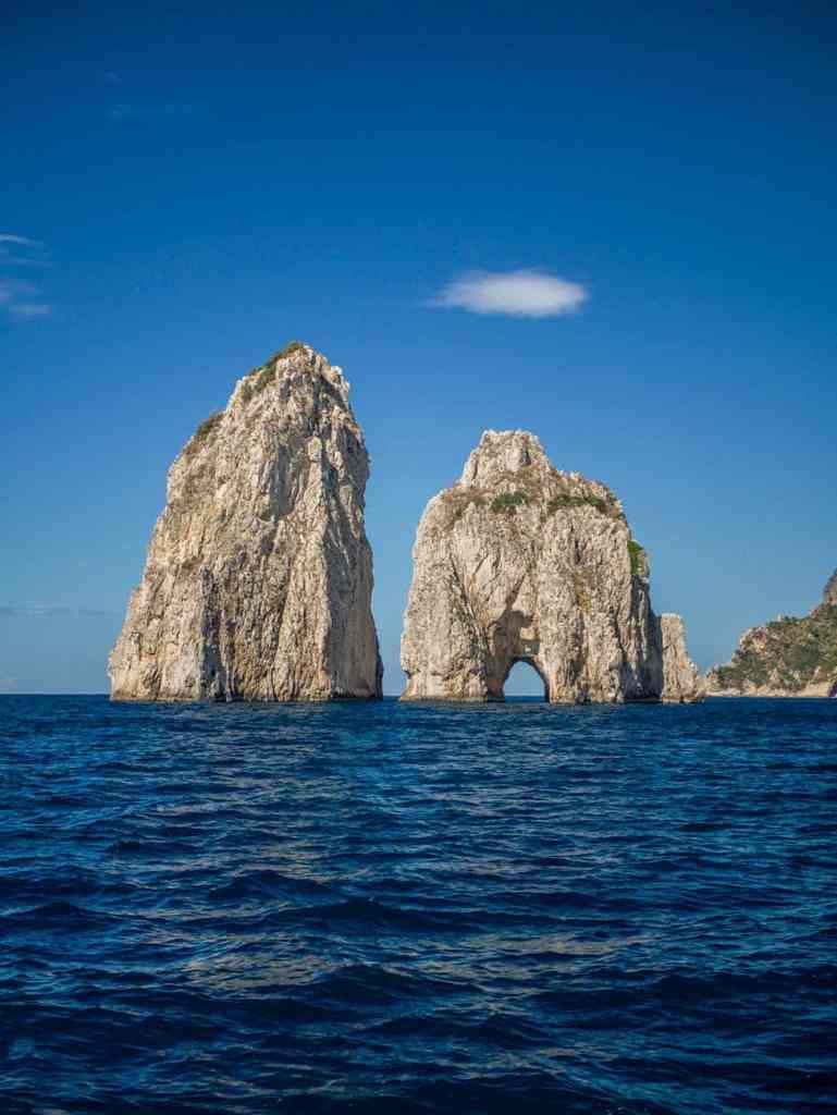brown rock formation on sea under blue sky