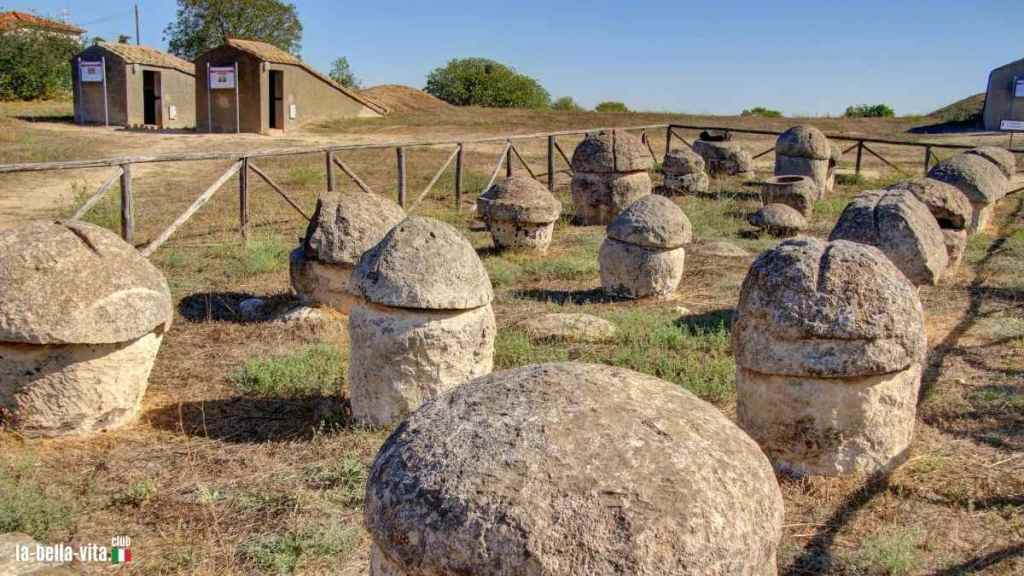 The necropolis of Tarquinia with tombs and lush vegetation, surrounded by cypresses and rolling hills. The archaeological site shows the living culture of the Etruscans.